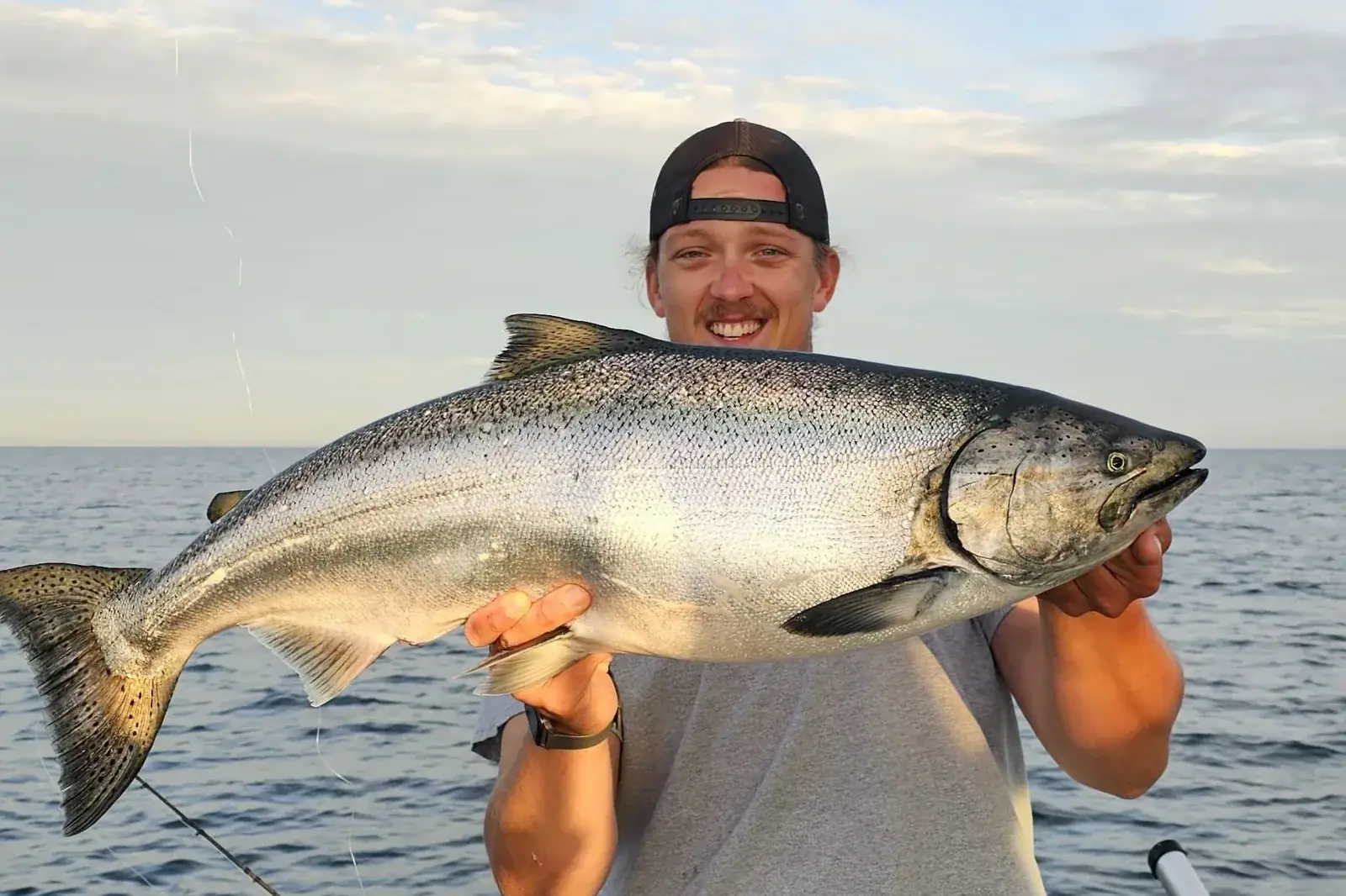 Angler holding a trophy chinook salmon at sunset on Lake Ontario