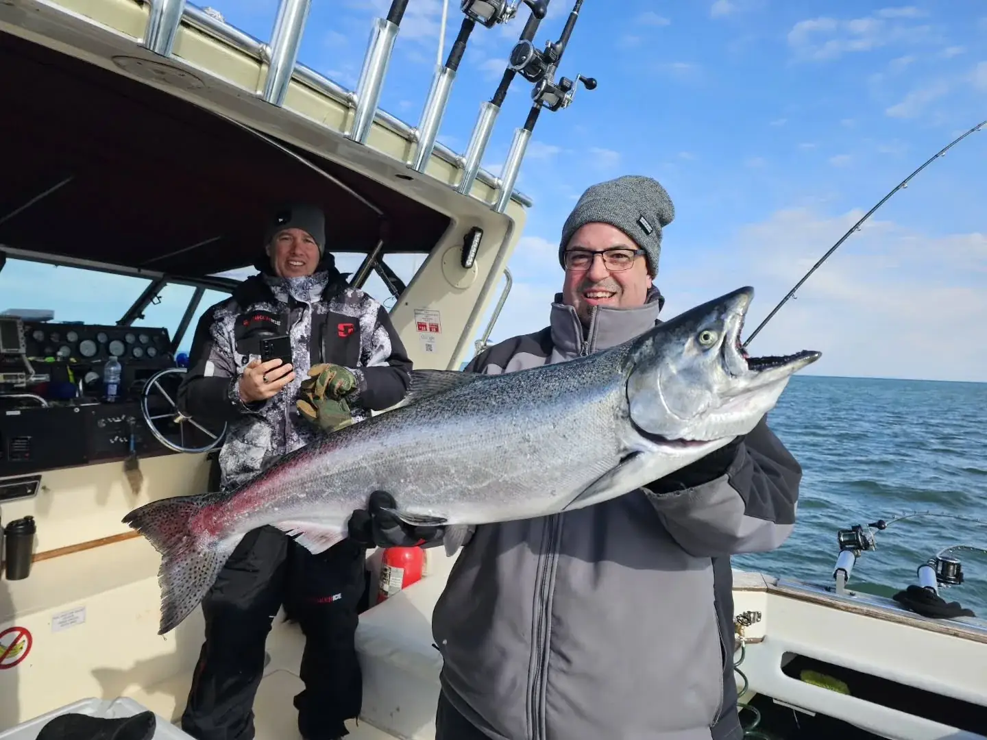 Two anglers holding chinook salmon aboard King Slayer under clear skies