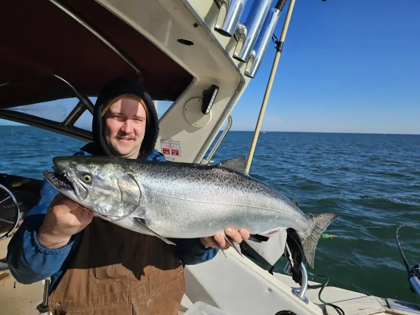 Angler holding a chinook salmon aboard King Slayer under blue skies