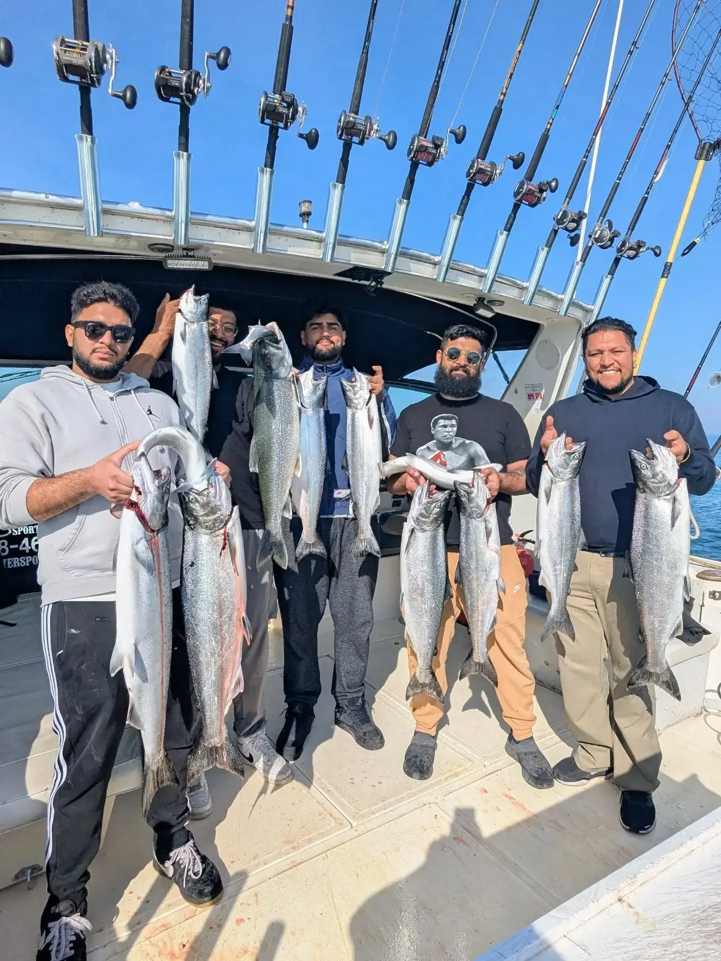 Five anglers under the rod rack holding a mixed catch of salmon and trout aboard King Slayer
