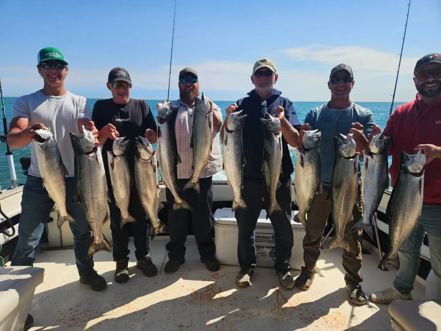 Six anglers lined up on a charter boat holding a full limit of chinook salmon
