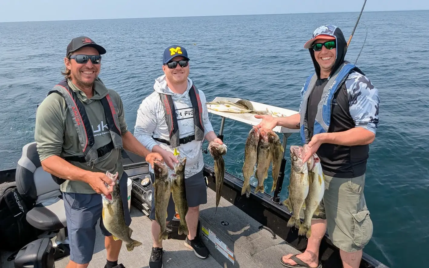 Three anglers holding up a catch of Lake Erie walleye out on open water