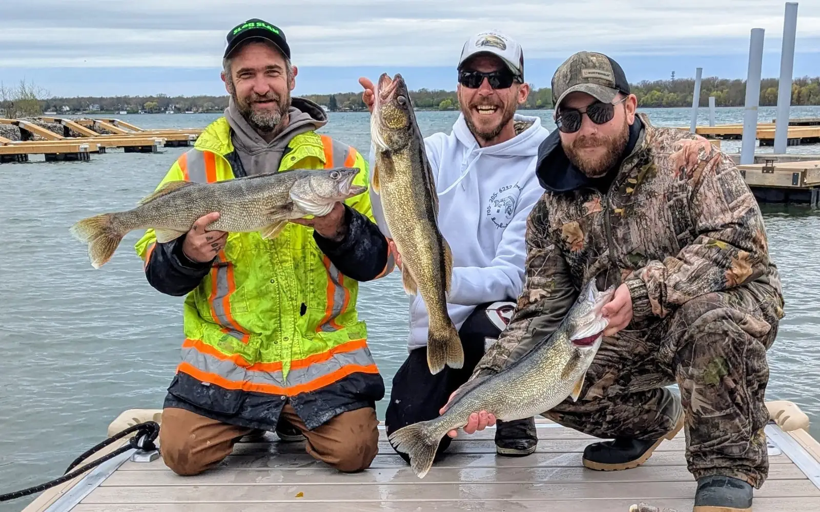 Three anglers on the dock holding Lake Erie walleye