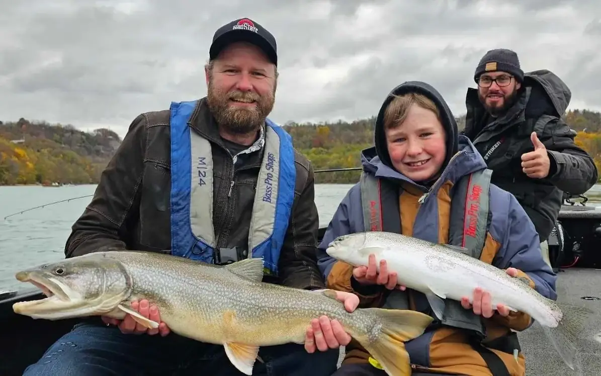 A family holding two river trout aboard the Alumacraft