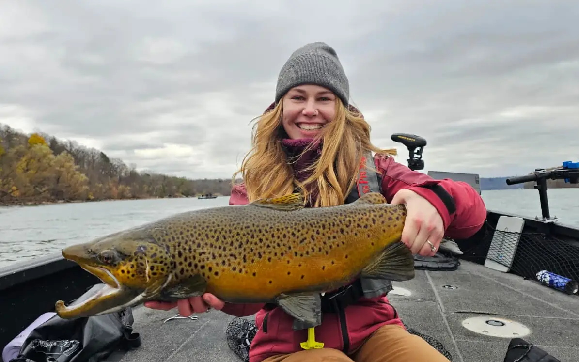 Angler holding a golden Niagara River brown trout against the autumn shoreline