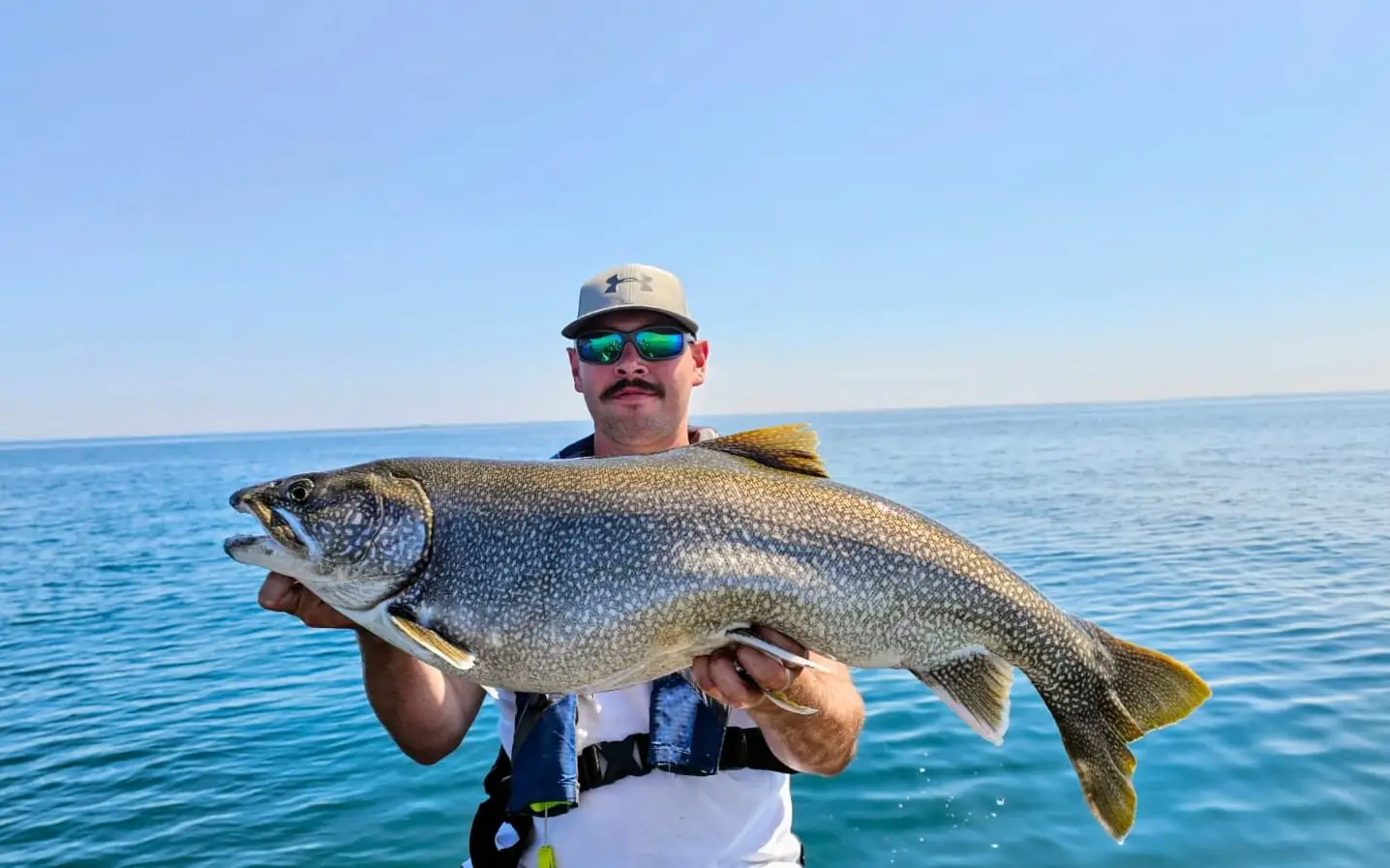 Angler holding a lake trout jigged up on Lake Ontario