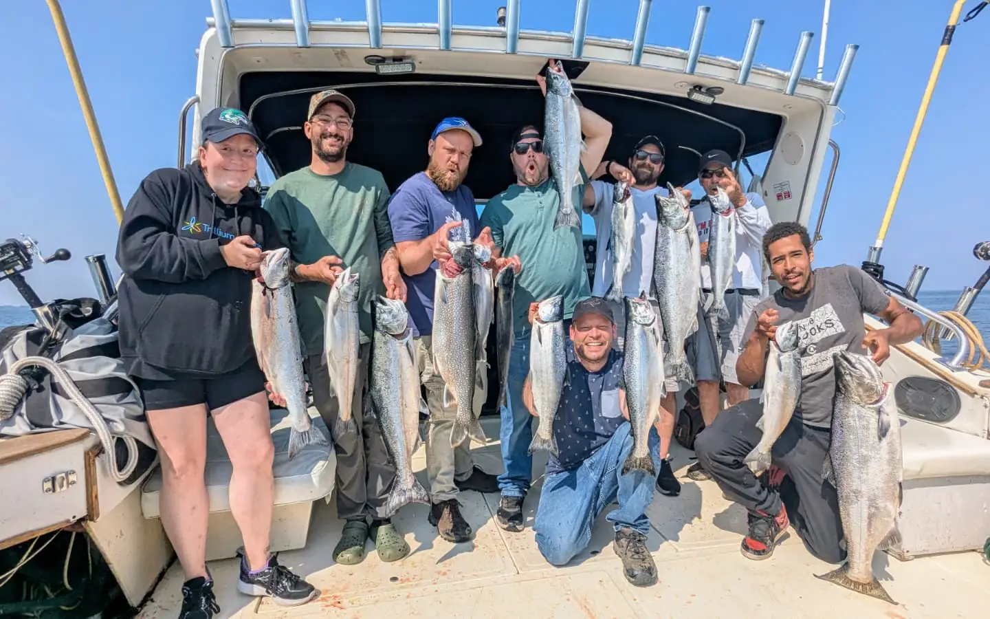 A full charter group holding up their catch of salmon and trout aboard King Slayer