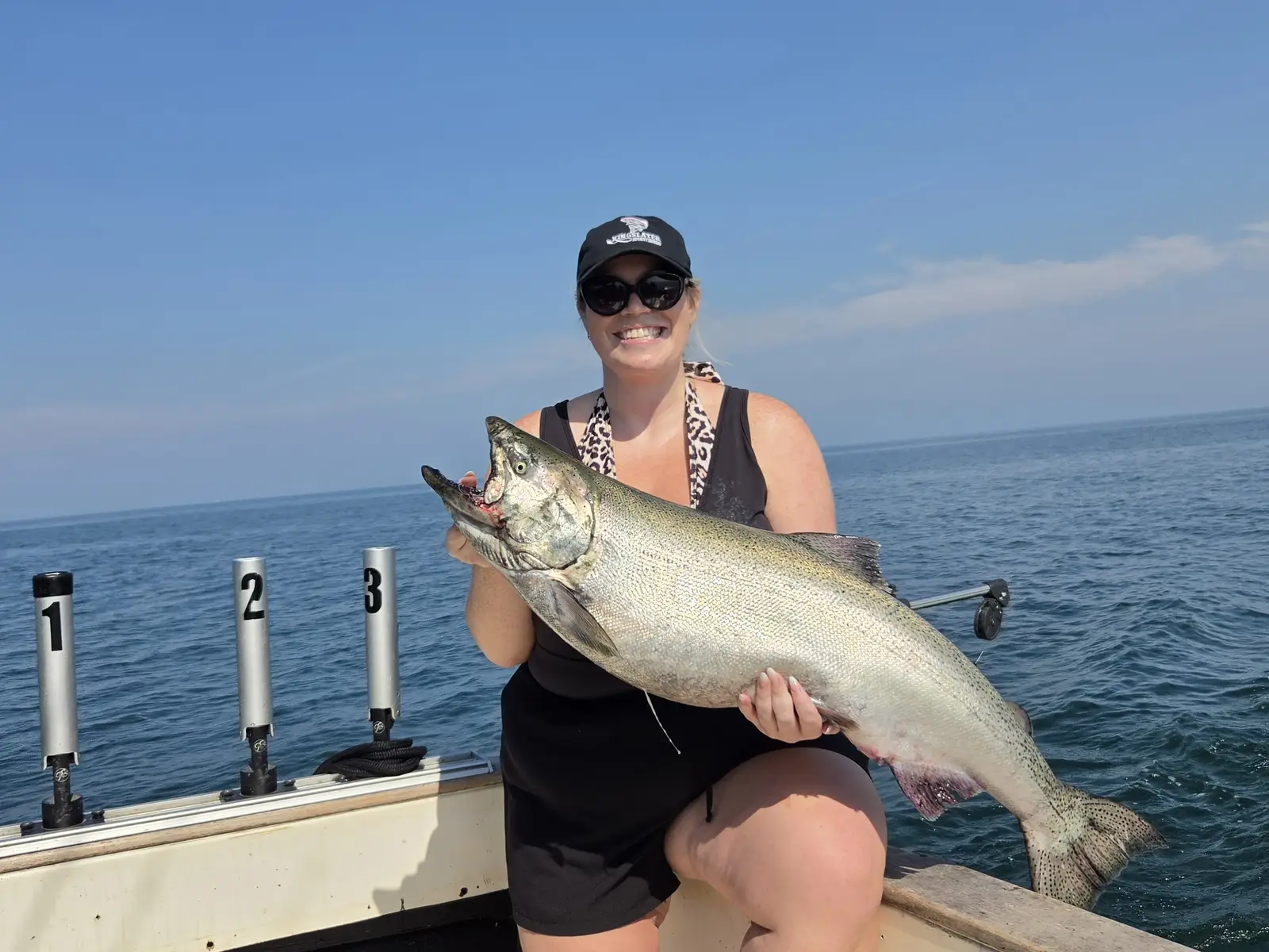 Guest holding a big chinook salmon on a sunny summer King Slayer charter on Lake Ontario