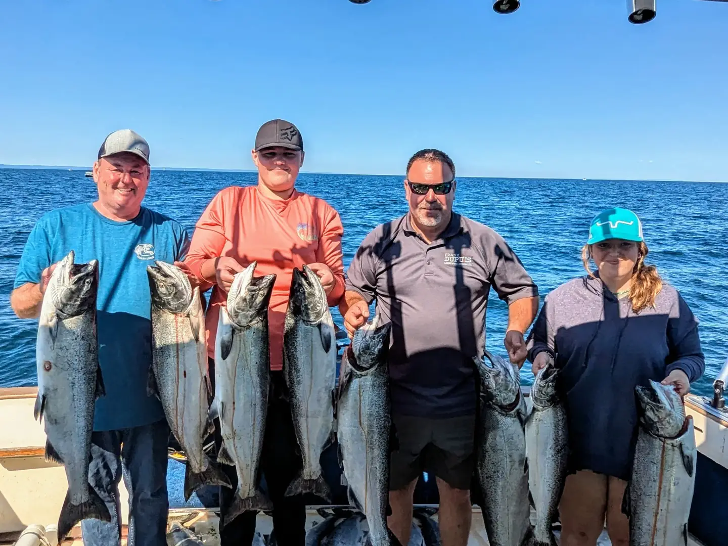 Four guests holding up their salmon in the late afternoon sun