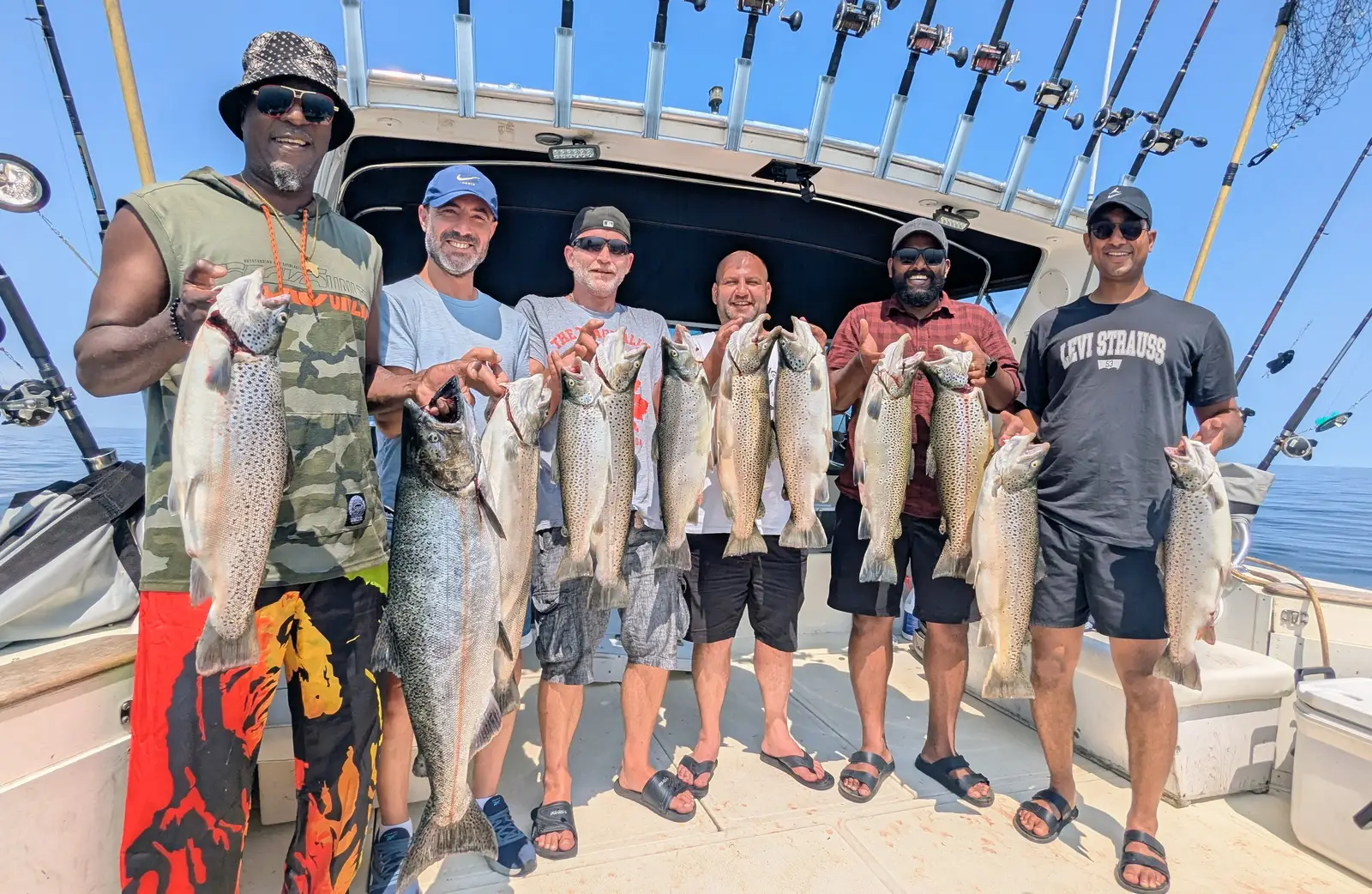 Six guests on the deck of a King Slayer Sea-Ray holding their Lake Ontario salmon and trout