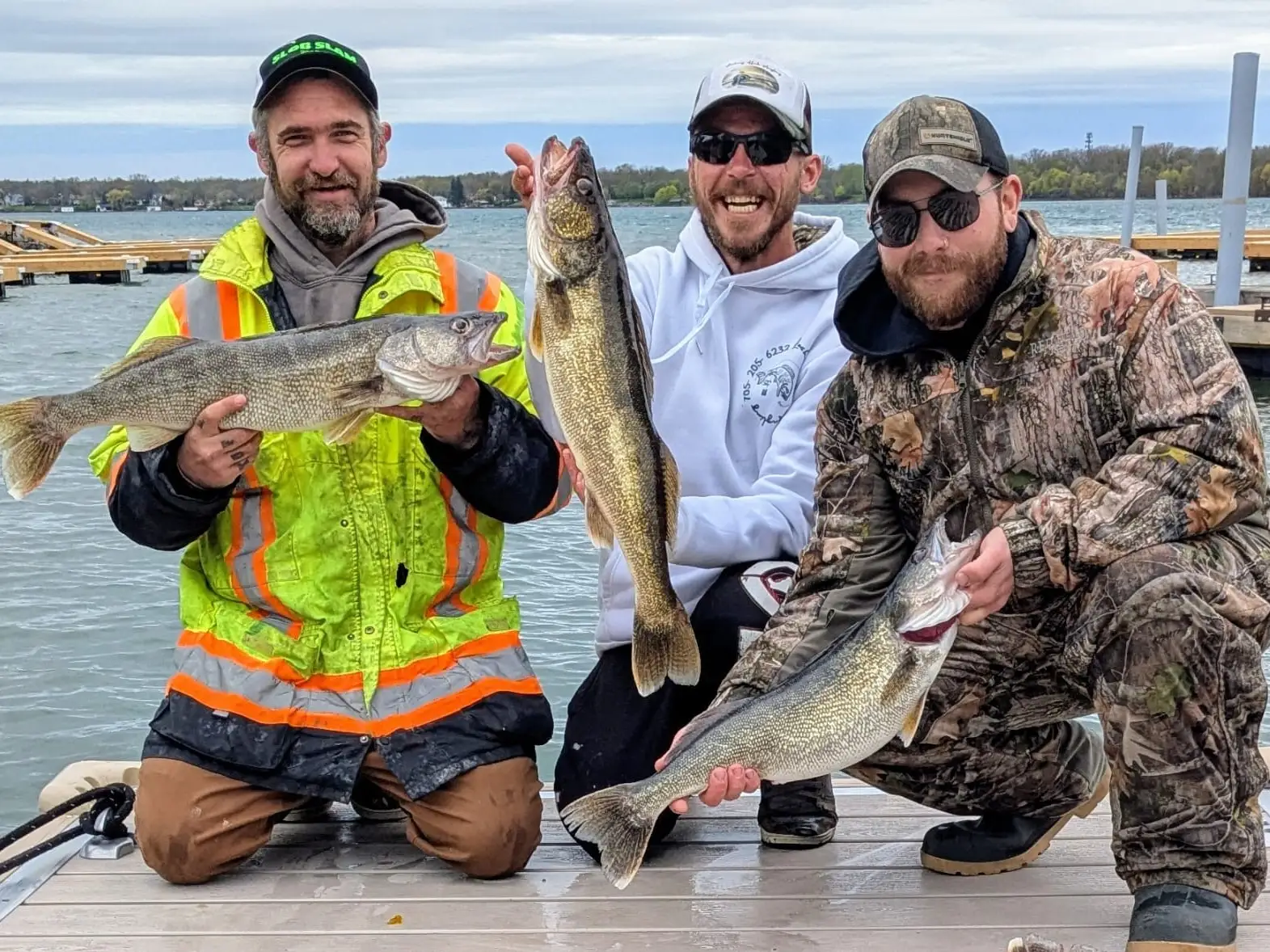 Three anglers on the dock holding Lake Erie walleye