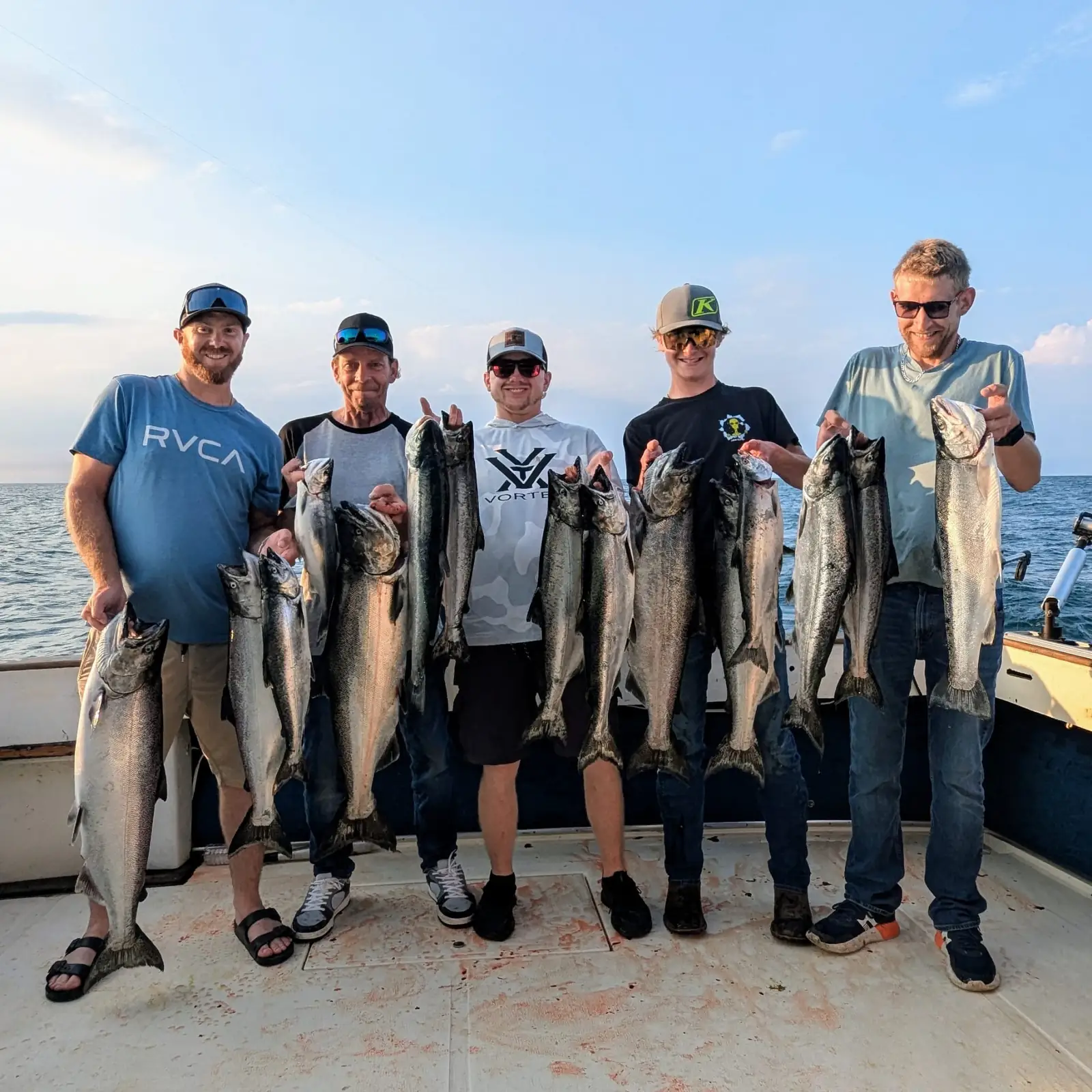 Five anglers on the King Slayer deck, each holding a pair of Lake Ontario salmon