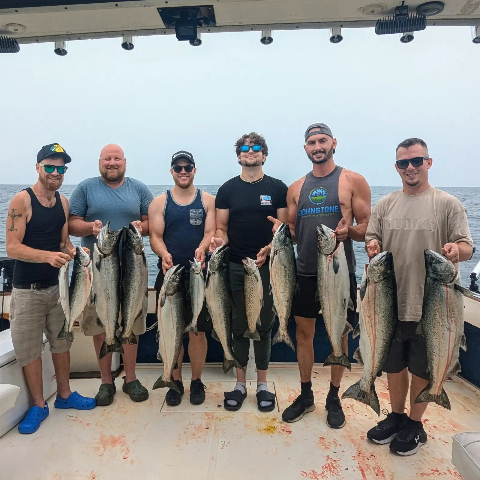 Six anglers lined up across the King Slayer deck with their Lake Ontario salmon and trout
